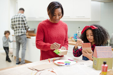 Mother and daughter painting cardboard houses