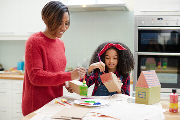 Mother and daughter painting cardboard houses