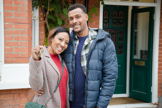 Portrait couple holding keys to new house outdoors