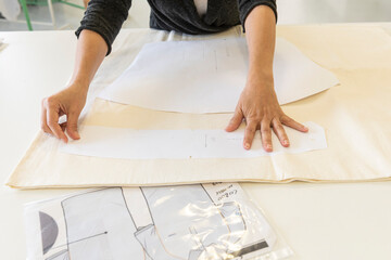 A woman draws and cuts a clothing pattern