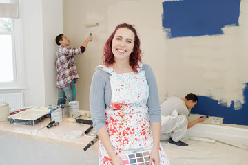 Portrait confident woman in overalls painting room with friends