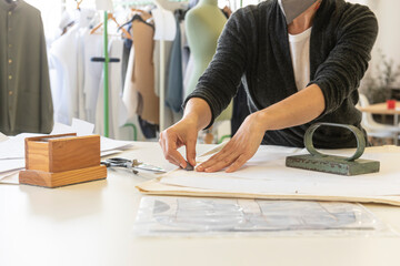 A woman draws and cuts a clothing pattern
