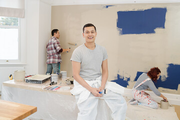 Portrait confident man painting room with friends