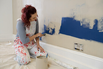 Woman in overalls painting wall
