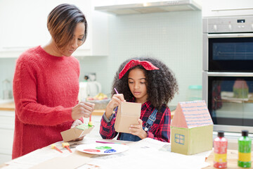 Mother and daughter painting cardboard houses