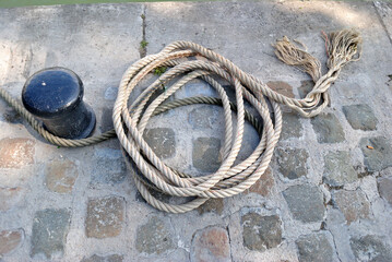 Close Up of Coiled Rope & Iron Bollard on Stone Quay 