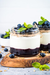 Parfait with blueberry, granola and jam in two glass jars. Healthy dessert or snack.