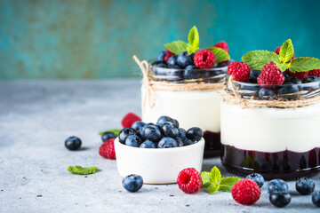 Parfait with cream or yogurt, jam and fresh berries in the glass jar. Close up. Healthy dessert or snack.
