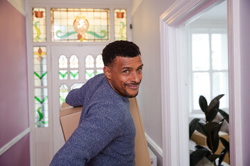 Portrait happy man carrying moving box in corridor