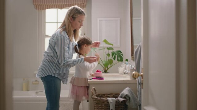 happy mother brushing daughter's hair in bathroom cute little girl getting ready in morning loving mom enjoying parenthood caring for child