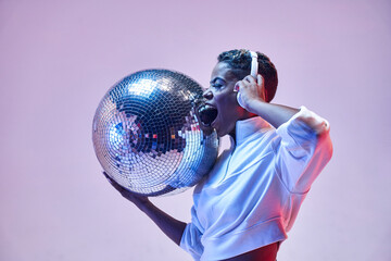 Trendy smiling black model in headphones with disco ball