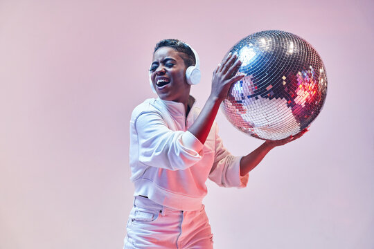 Trendy smiling black model in headphones with disco ball
