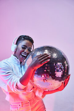 Trendy smiling black model in headphones with disco ball
