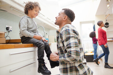 Obraz premium Father putting shoes on son