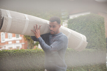 Man carrying rug through front door