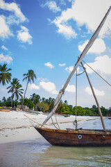 Moored boat on the beach. Wooden local boat on coastline, Zanzibar. Fishing village in Africa. Scenic coastline with palm trees, sandy beach and fishing vessels. Tropical vacations. Island life. 