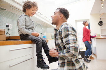 Obraz premium Father putting shoes on son