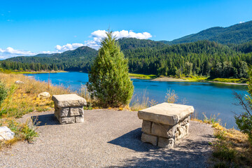 Two small stone benches in a small park rest area along the highway facing Pend Oreille River near the town of Metaline Falls, Washington, USA