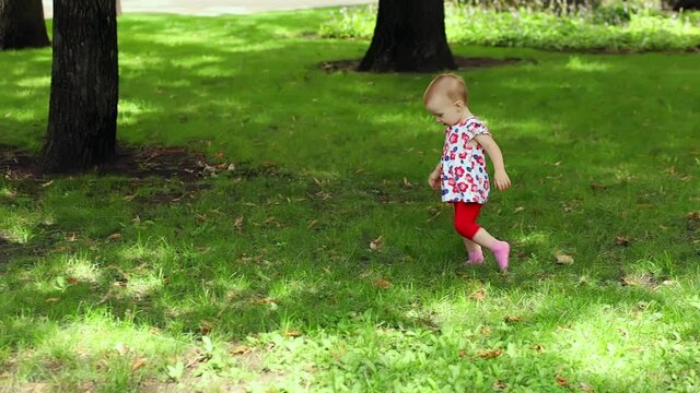 A little girl runs on the lawn of a city park
