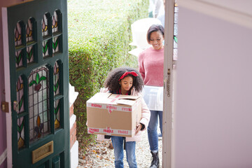 Happy family moving into new house, carrying cardboard boxes in corridor