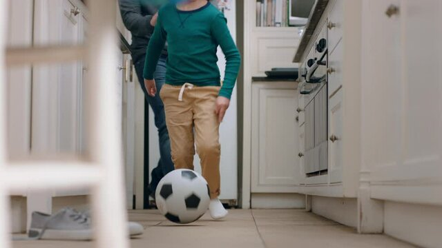father and son playing with football in kitchen kicking soccer ball child enjoying game with dad at home 