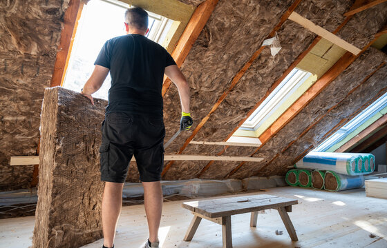 Craftsman cutting insulation material to insulate the attic.