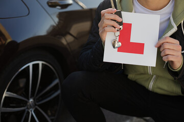 Portrait confident, happy young man holding learners permit by car