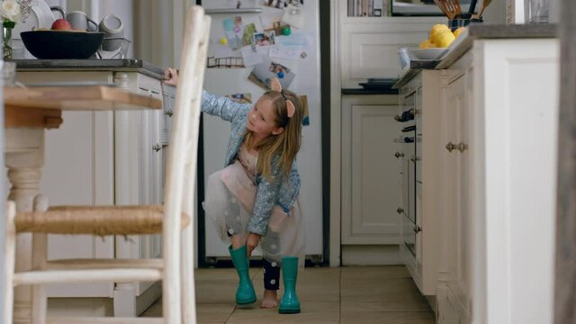 beautiful little girl wearing pretty dress putting on boots having fun at home playing pretend game enjoying childhood imagination
