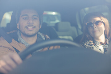 Happy young couple wearing sunglasses in car