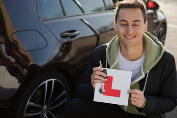 Portrait confident, happy young man holding learners permit by car