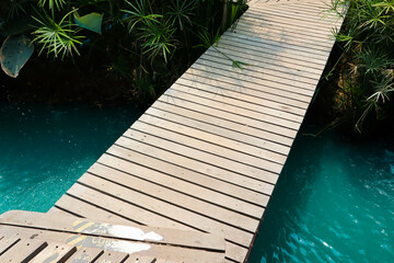 Bangkok, Thailand - April 20, 2020 : Wooden bridge crossing river in garden..