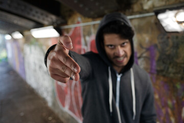 Portrait menacing young man gesturing finger gun in urban tunnel