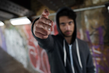 Portrait menacing young man gesturing finger gun in urban tunnel