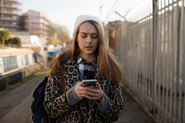 Portrait smiling young woman with smart phone on urban sidewalk