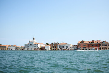 Venetian gondolier punting gondola through green canal waters of Venice Italy
