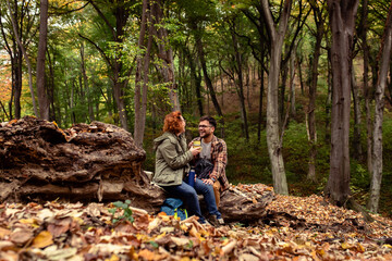 Young couple with backpack resting after hiking in forest.