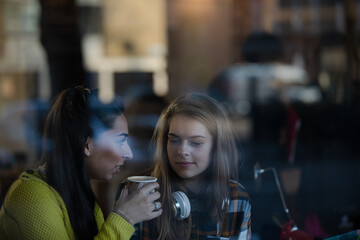 Young female college students studying at laptop in cafe window