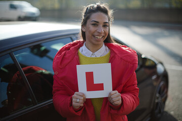 Portrait confident, happy young woman holding learners permit by car