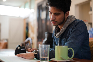 Portrait confident young male college student studying in cafe