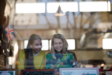 Young female college students studying at laptop in cafe window