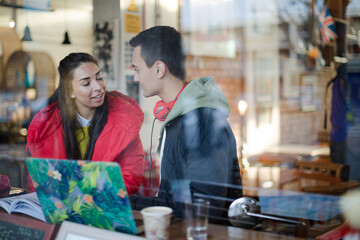 Young couple studying at cafe window