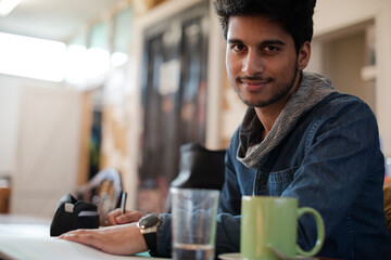 Portrait confident young male college student studying in cafe