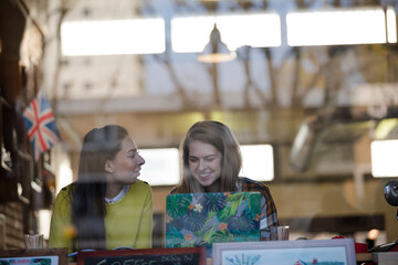 Young female college students studying at laptop in cafe window