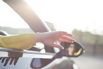 Carefree woman reaching hand out car window