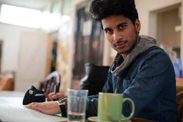 Portrait confident young male college student studying in cafe