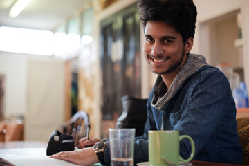 Fototapeta na wymiar Portrait confident young male college student studying in cafe