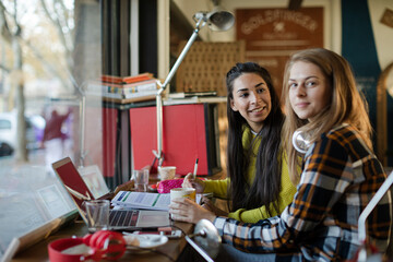 Portrait smiling female college students studying at laptop in cafe