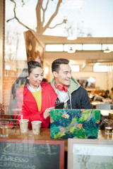 Young couple using smart phone and laptop in cafe