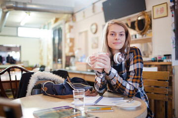 Portrait confident young female college student studying at cafe table