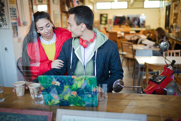 Young couple using smart phone and laptop in cafe